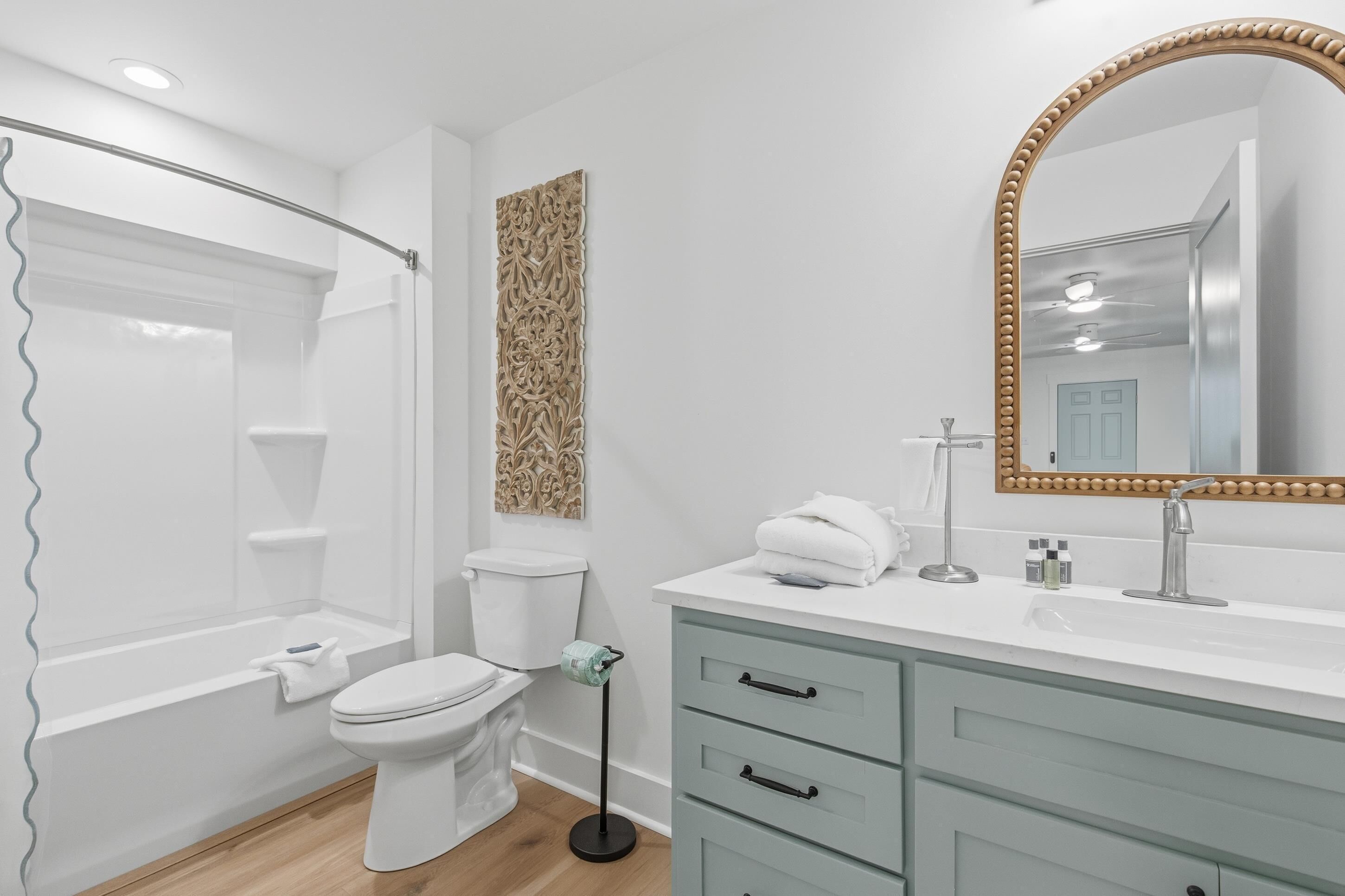 A modern bathroom with a shower, toilet, vanity, and a large mirror.