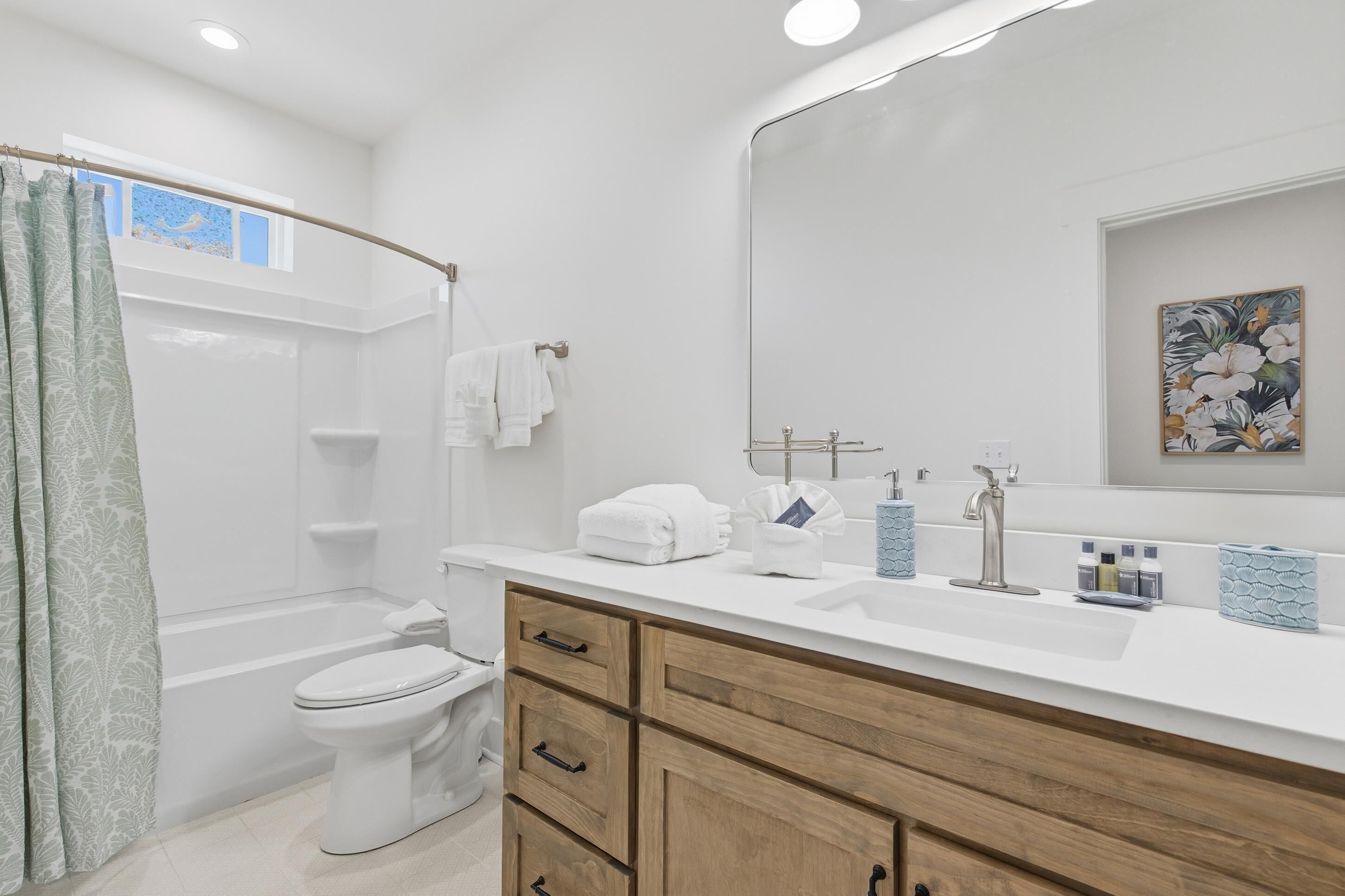 A modern bathroom with a bathtub, toilet, and vanity with a mirror and sink.
