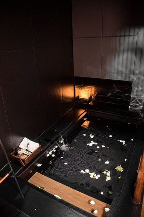 A dark room with a small water feature, a wooden bench, and a candle on a table. - WUTA Designer Hotel (Chaozhou)