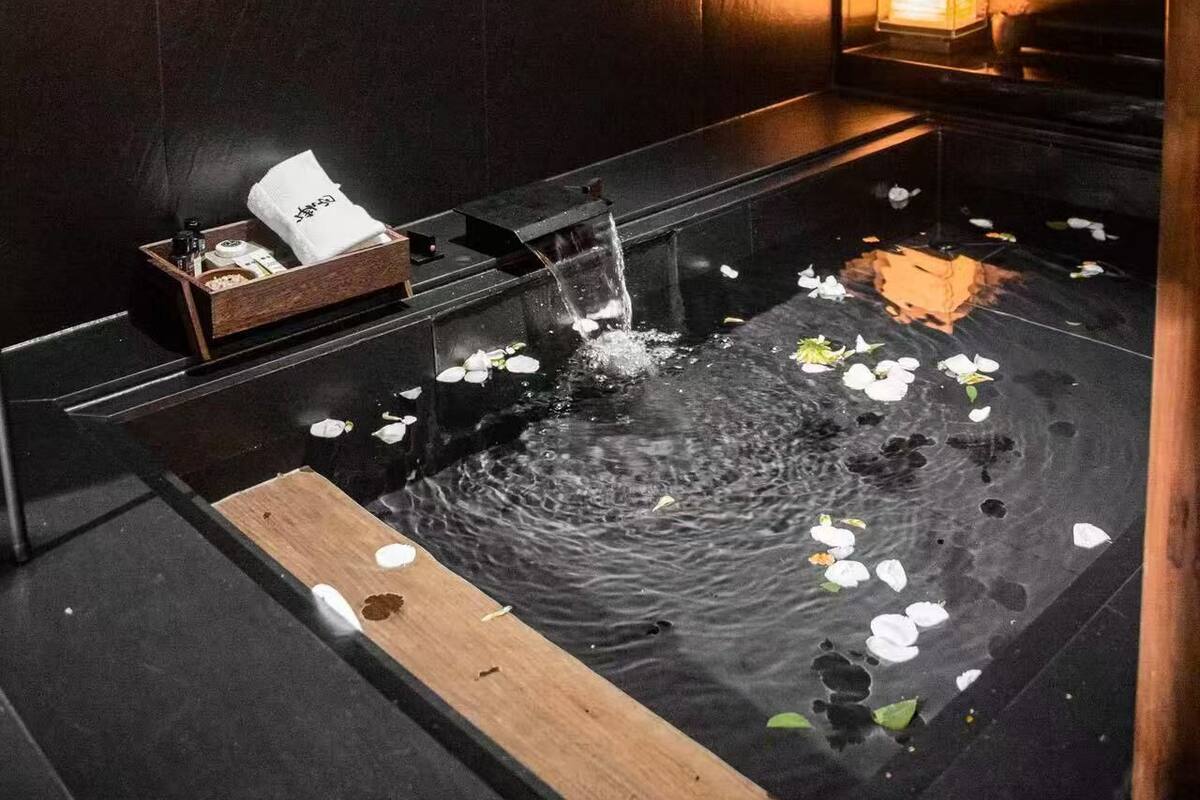 A room with a water feature, a wooden tray, and a small table with a white cloth and items.