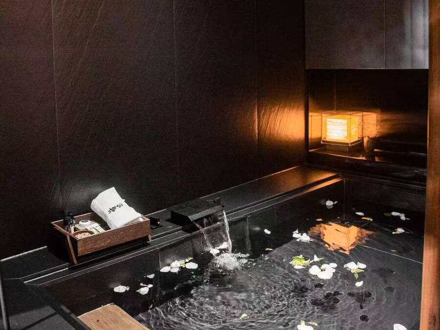 A room with a water feature, a wooden tray, and a small table with a white cloth and items.