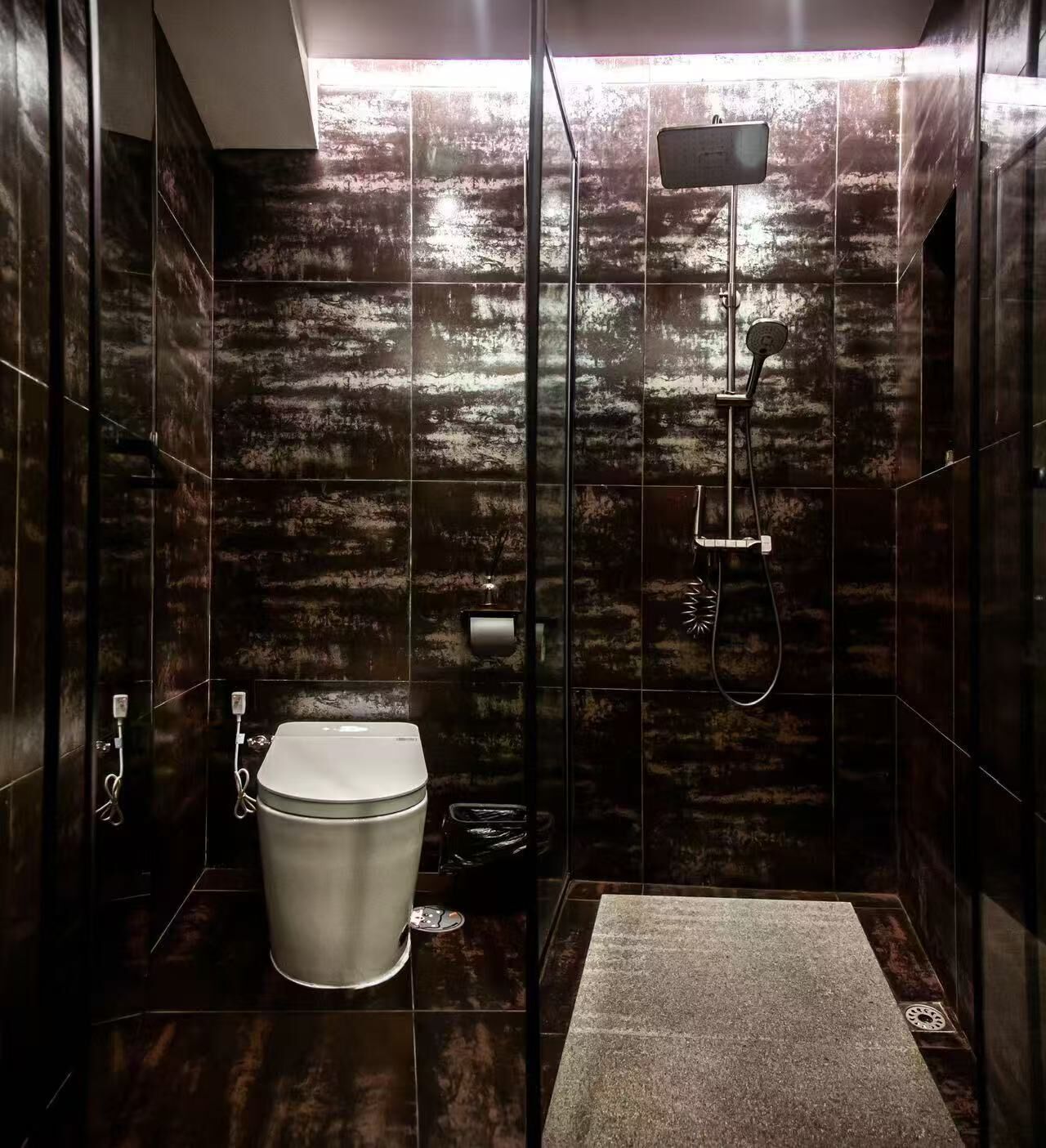 Un baño moderno con inodoro, ducha y una alfombra en el suelo.