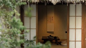 Um quarto japonês tradicional com tatames, uma porta de tela shoji e uma mesa de madeira baixa com um conjunto de chá.