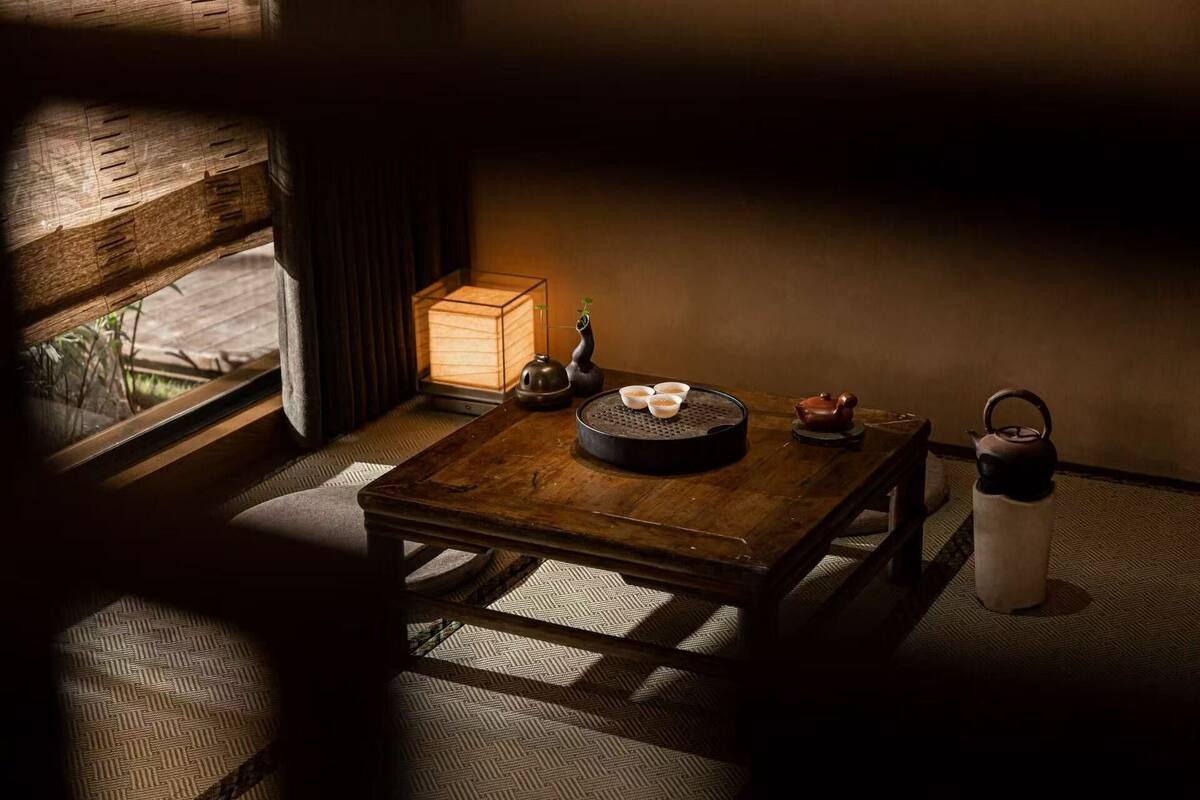 A traditional Japanese-style room with tatami flooring, a low wooden table, a tea set, and a lantern.