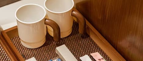 A wooden drawer with two white mugs and a box of cigarettes.