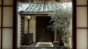 Uma entrada japonesa tradicional com porta de madeira, um candeeiro de pedra e um telhado de palha.