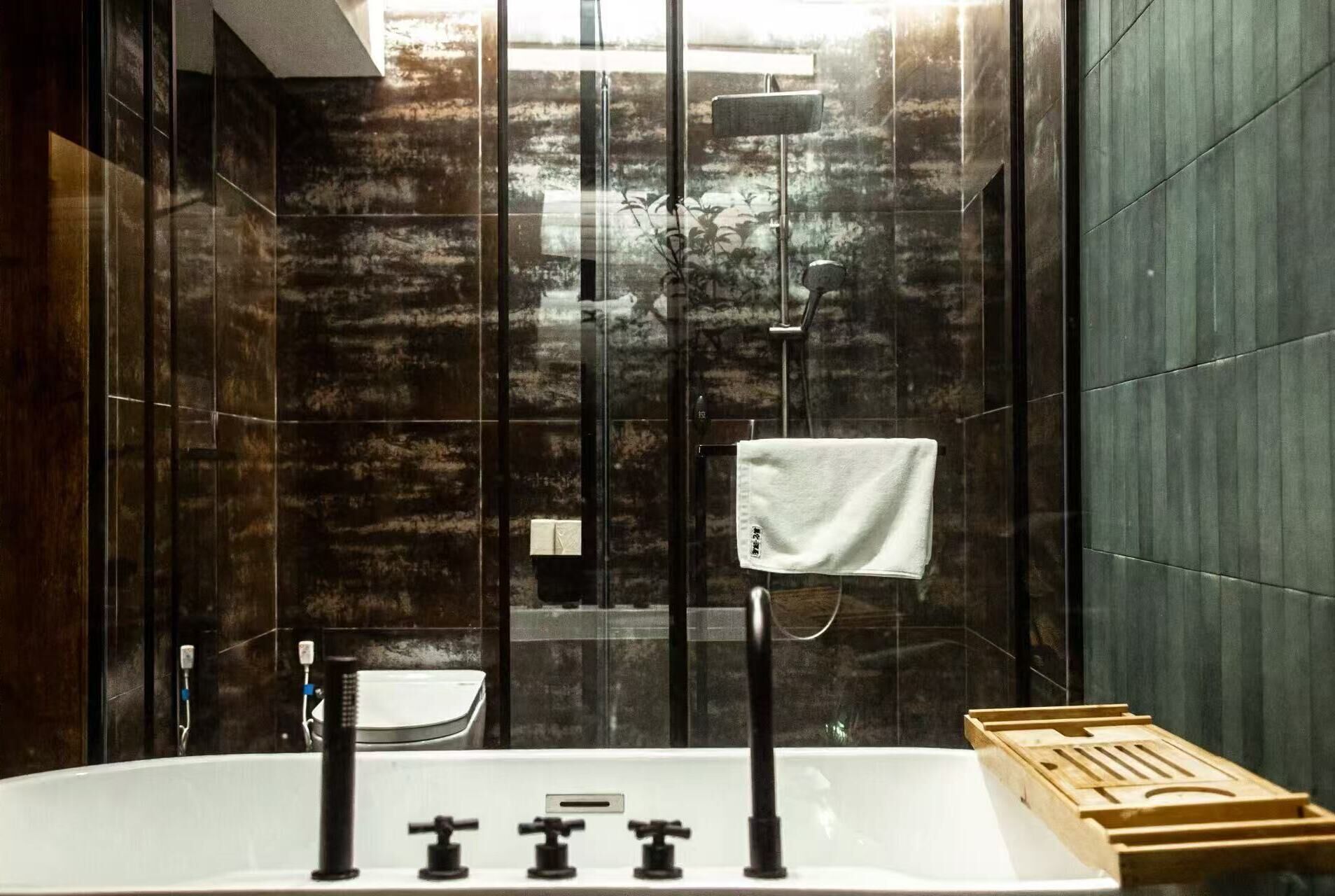 Un baño moderno con una bañera independiente, un perchero y una bandeja de madera.