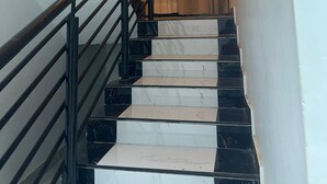 A staircase with black railings and marble steps leading up to a landing with a curtain. - Spacious 5-bedroom apartment in serene Haatso Atomic Road with AC (Haatso)