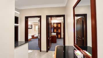 A hotel corridor with a reception desk, a mirror, and a room with a bed and a desk.