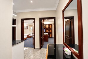 A hotel corridor with a reception desk, a mirror, and a room with a bed and a desk. - MG Crown Hotel 3 (Madinah)