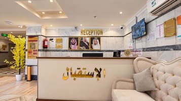 A reception area with a marble reception desk, a sofa, and a wall-mounted TV.