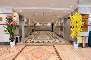 A hotel lobby with a marble floor, a reception desk, and potted plants. - MG Crown Hotel 3 (Madinah)