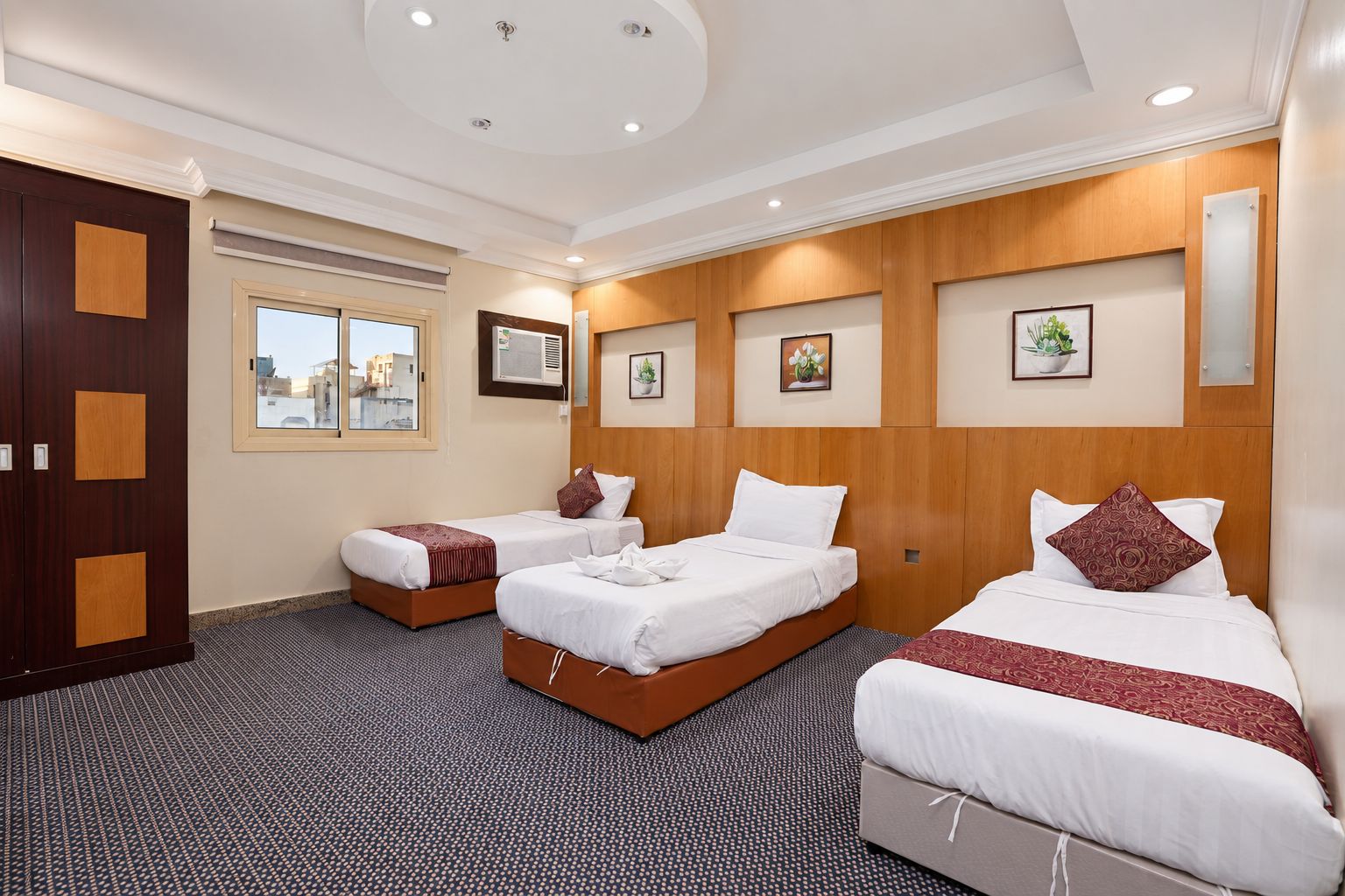 A hotel room with two single beds, a large window, and a city view.
