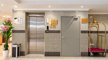 Un ascensor, una porta i un carro amb un coixí vermell a la zona del vestíbul.