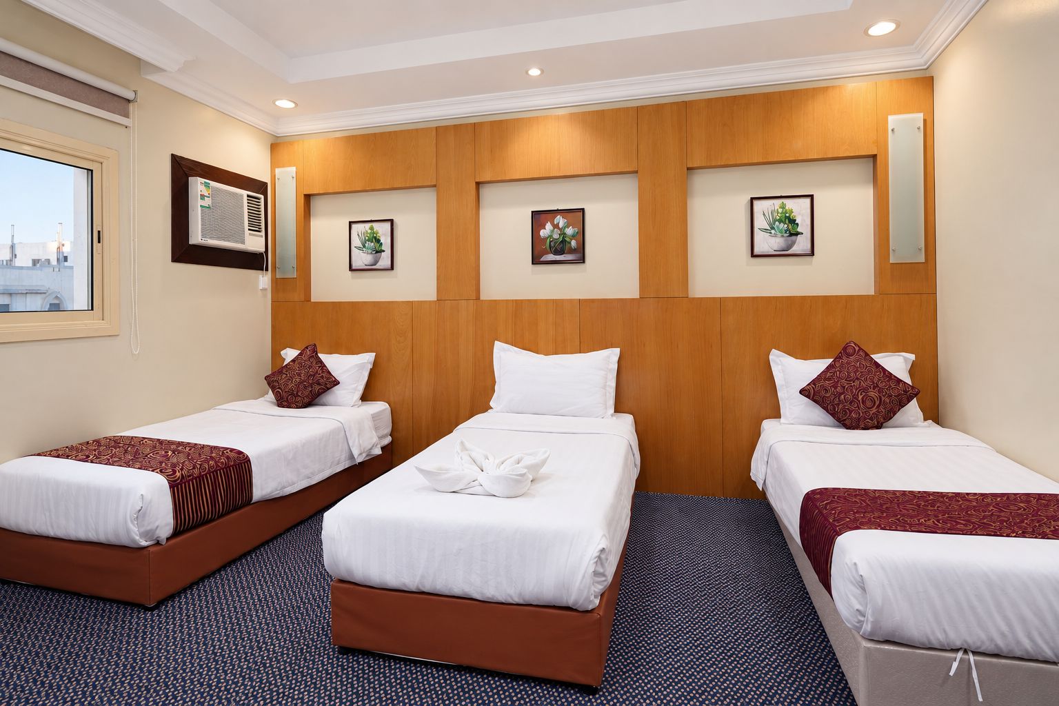 A hotel room with three beds, a large window, and a view of the city.