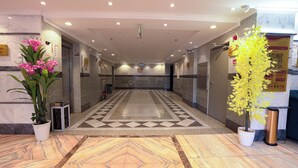 Eine Hotelhalle mit Marmorboden, Blumentöpfen und einer Rezeption.