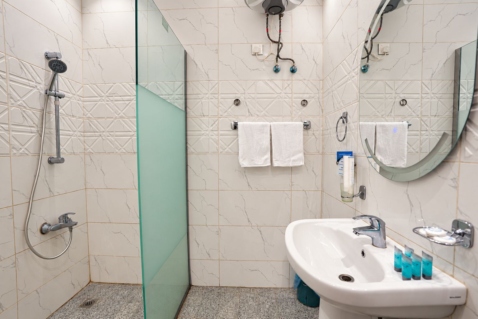 A bathroom with a shower, a sink, and a mirror.