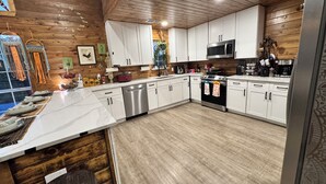 A modern kitchen with white cabinets, stainless steel appliances, and a wooden ceiling. - Stunning and private lake front sunrise and sunset views! (Nevada)