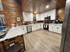 Een moderne keuken met witte kastjes, roestvrijstalen apparatuur en een houten plafond.