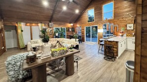 A spacious living area with a high ceiling, wooden walls, and a dining area with a bar. - Stunning and private lake front sunrise and sunset views! (Nevada)