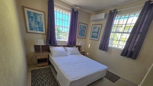 Habitación de hotel con una cama grande, dos mesitas de noche, aire acondicionado instalado en la pared y cuadros enmarcados.