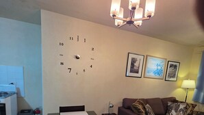 Una sala de estar con una mesa de comedor, un sofá y un reloj de pared.