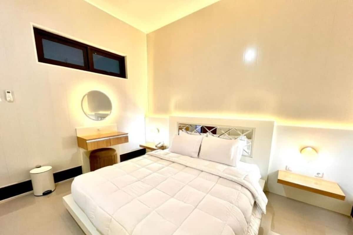 A bedroom with a large bed, bedside tables, a mirror, and a nightstand.