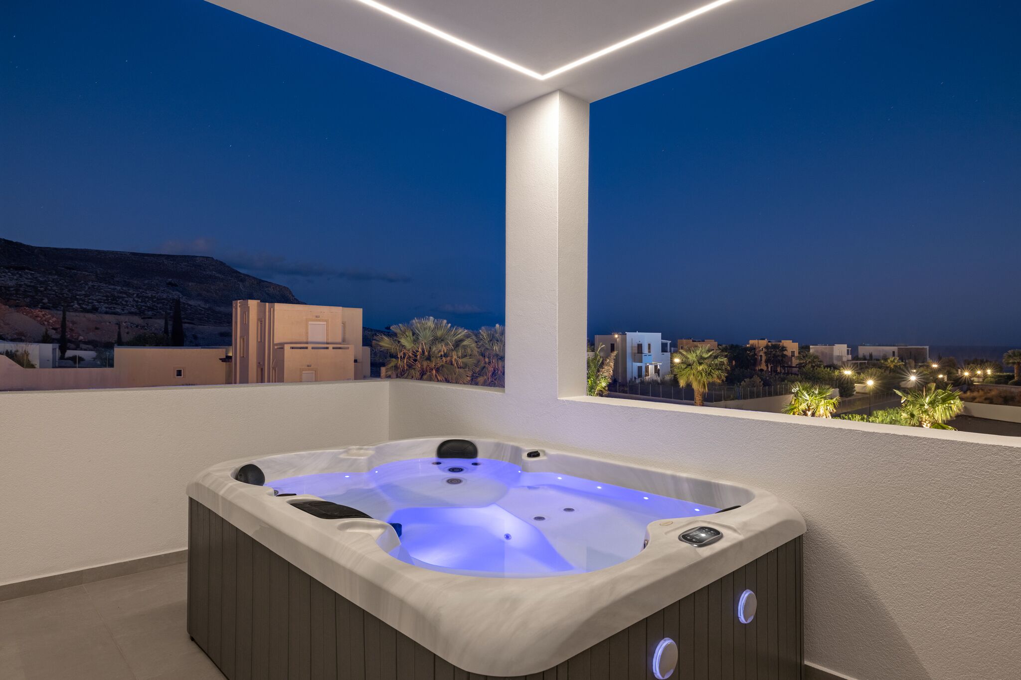 A hot tub on a balcony with a city view at dusk.