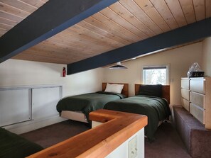 A room with two beds, a wooden ceiling, a window, and a dresser. - Cozy Mountain Condo Steps from the Main Lift (Taos Ski Valley)
