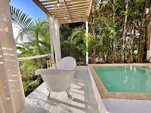 A white bathtub in a covered outdoor area with a pool, surrounded by lush greenery. - Private Pool Suite with outdoor tub in Rincon (Rincón)
