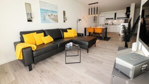 Een moderne woonkamer met een zwarte modulaire bank, een salontafel en een keuken op de achtergrond.