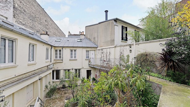 A courtyard with buildings, a stone pathway, and various potted plants. - Cozy Studio 2P - Montmartre (Paris)