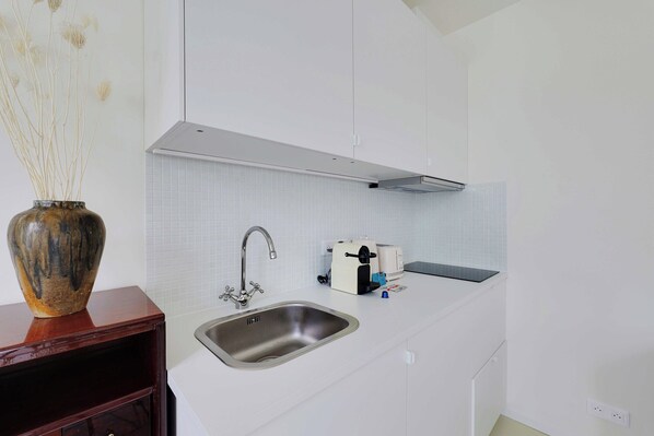 A modern kitchen with a stainless steel sink, a toaster, and a vase with dried plants on a wooden shelf. - Cozy Studio 2P - Montmartre (Paris)