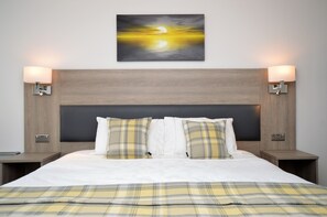 A hotel room with a large bed, two bedside tables, a headboard, and a wall-mounted painting of a sunset. - Fyne Rooms - Jura Superior King - Bed & Breakfast (Tighnabruaich)