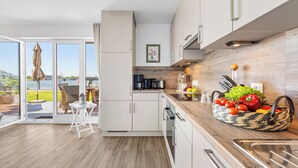 Eine moderne Küche mit weißen Schränken, einer Holz Arbeitsplatte und einem Korb frischem Gemüse.