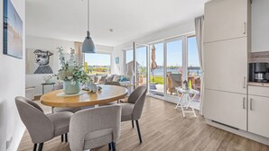 Eine moderne Küche mit Essbereich, großen Fenstern und Blick ins Freie.