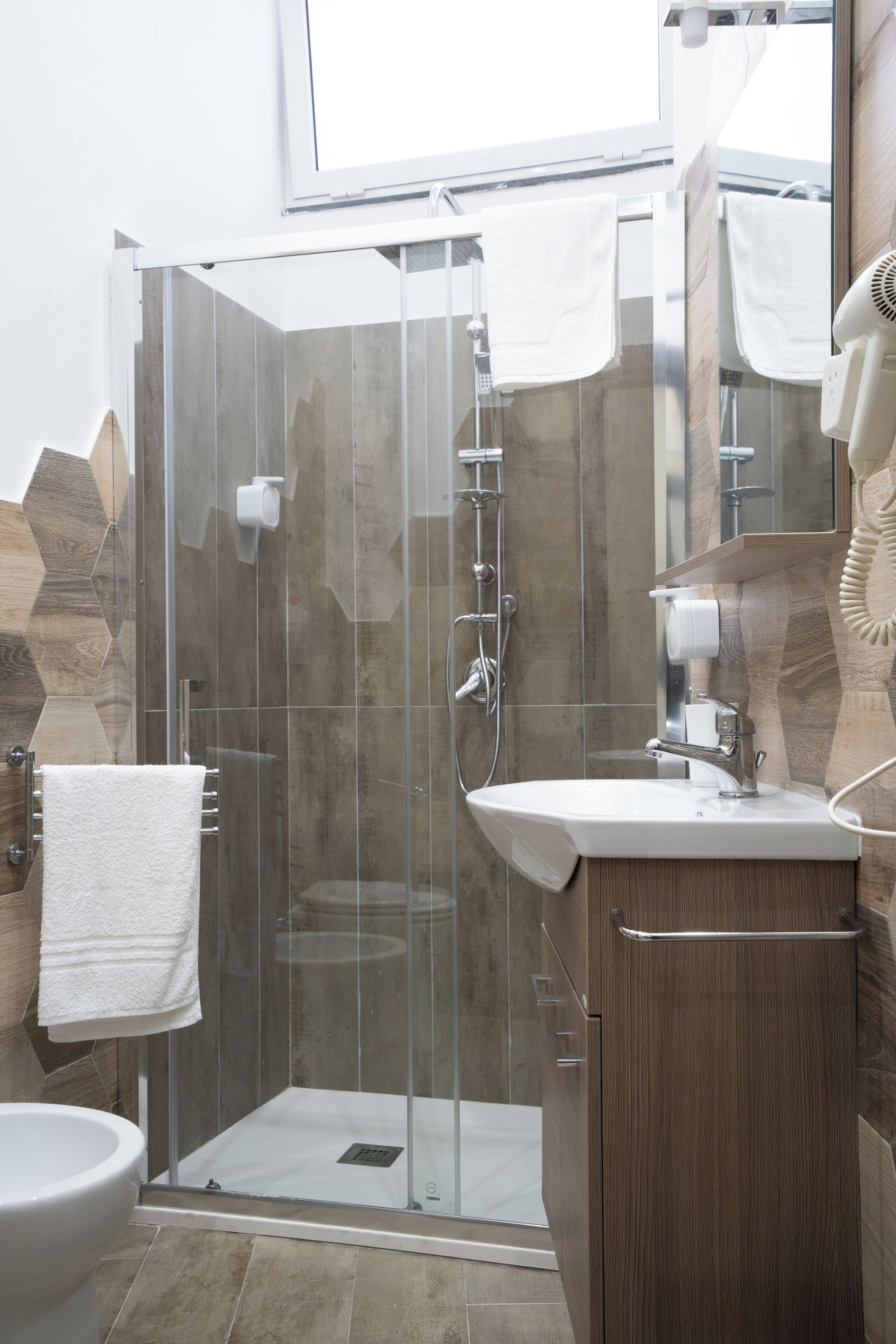A modern bathroom with a glass-enclosed shower, a white sink, and a wooden vanity.