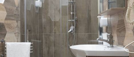 A modern bathroom with a glass-enclosed shower, a white sink, and a wooden vanity.