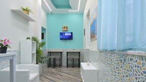 A reception area with a TV, seating, and a mosaic wall. - La dimora del Sole (Ercolano)