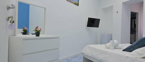 A bedroom with a bed, a dresser, a TV, and a painting on the wall.