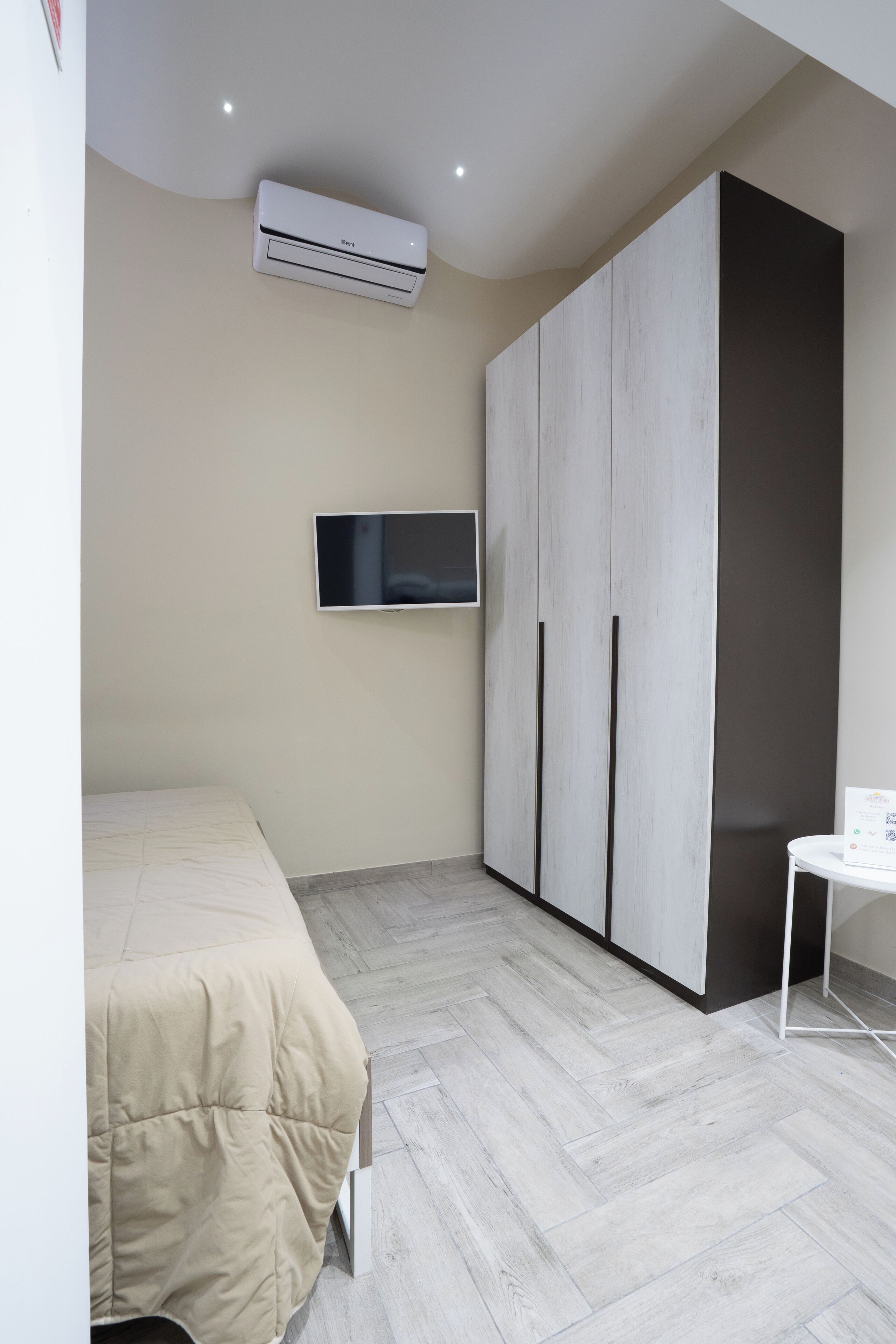A bedroom with a bed, an air conditioner, a TV, and a wardrobe.