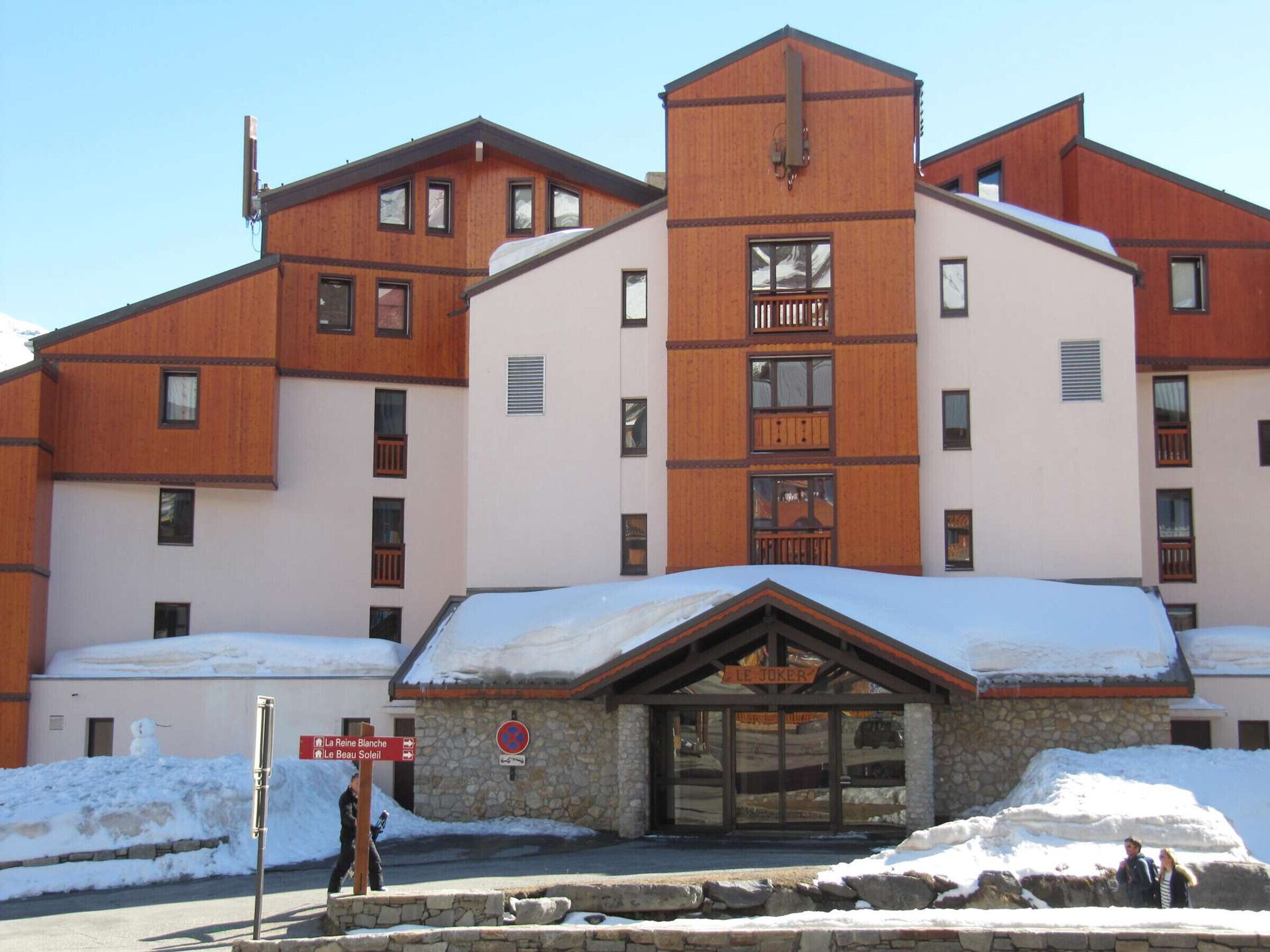 Un edificio a più piani con facciata in pietra e dettagli in legno, caratterizzato da un ingresso ben visibile con un'insegna che riporta 
