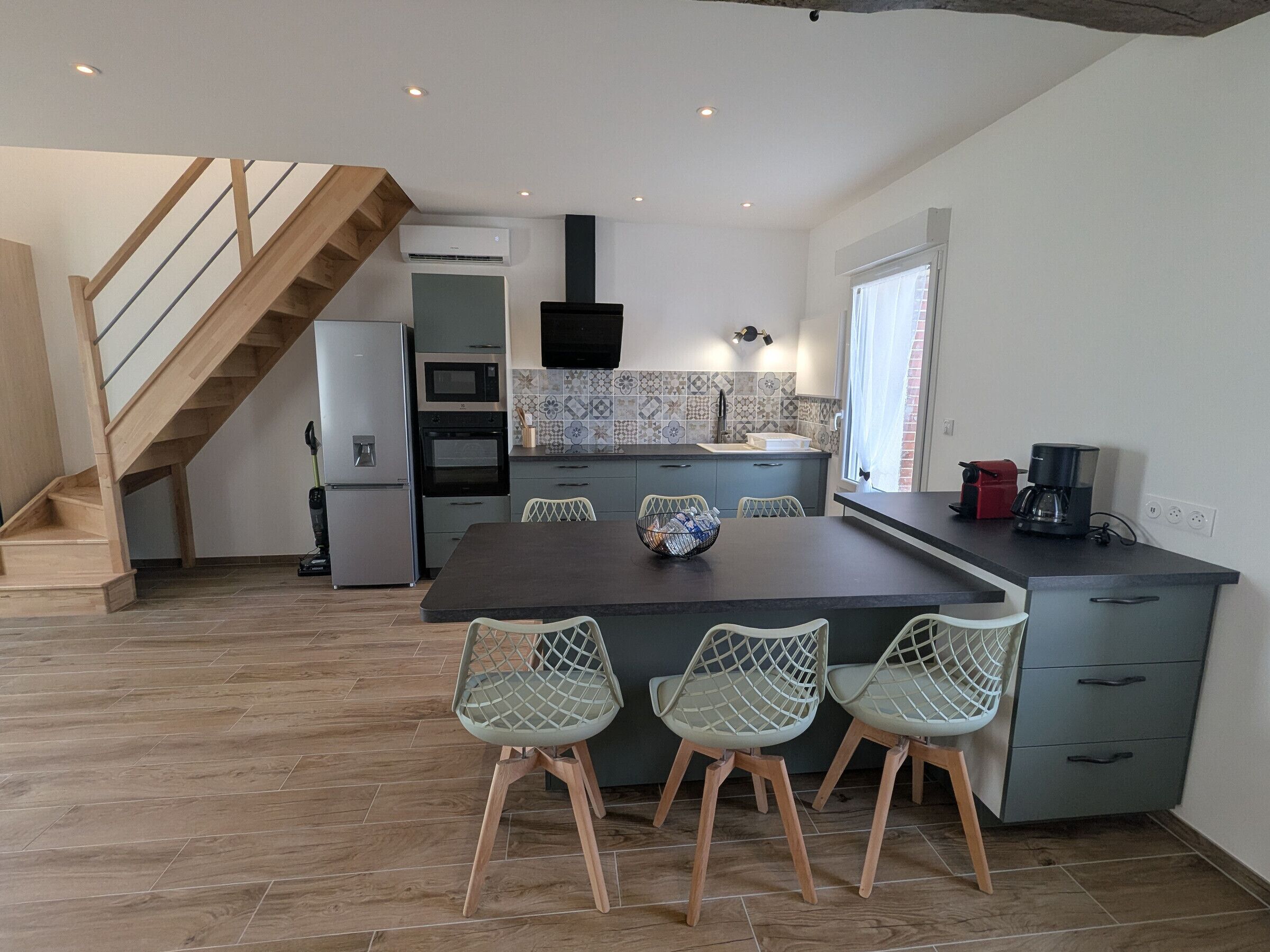 Una cucina moderna con zona pranzo, caratterizzata da una scala in legno, elettrodomestici integrati e una parete backsplash piastrellata.