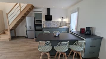 Una cucina moderna con zona pranzo, caratterizzata da una scala in legno, elettrodomestici integrati e una parete backsplash piastrellata.