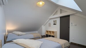 Een slaapkamer met twee bedden, een dakraam en een houten hoofdbord.