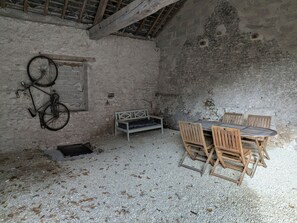A rustic room with a wooden table and chairs, a bench, and a bicycle leaning against the wall.