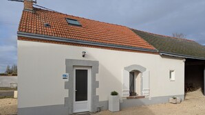 Een laag gebouw met een rode dakbedekking, een witte gevel en een klein raam.