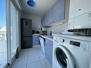 Eine kleine Küche mit Waschmaschine, Kühlschrank und Mikrowelle.