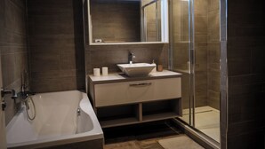 Een moderne badkamer met een bad, een wastafel met een grote spiegel, en een douchecabine van glas.