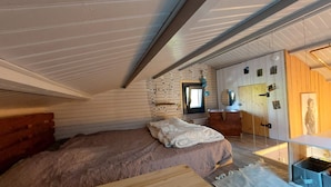 A cozy attic bedroom with a bed, wooden headboard, and a small wooden table.